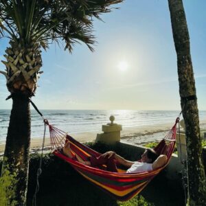 Peaceful moment of Dr. Gulani enjoying a beachside hammock, embodying his message of stepping out—not just hanging in.